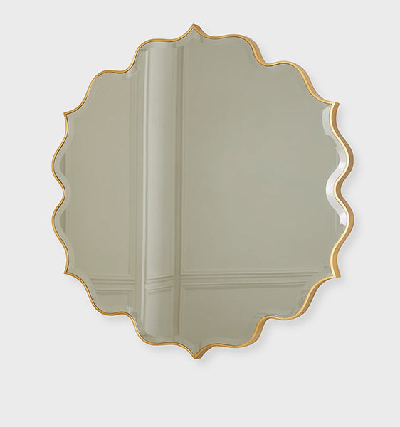 A round brass mirror with a floral pattern on the frame