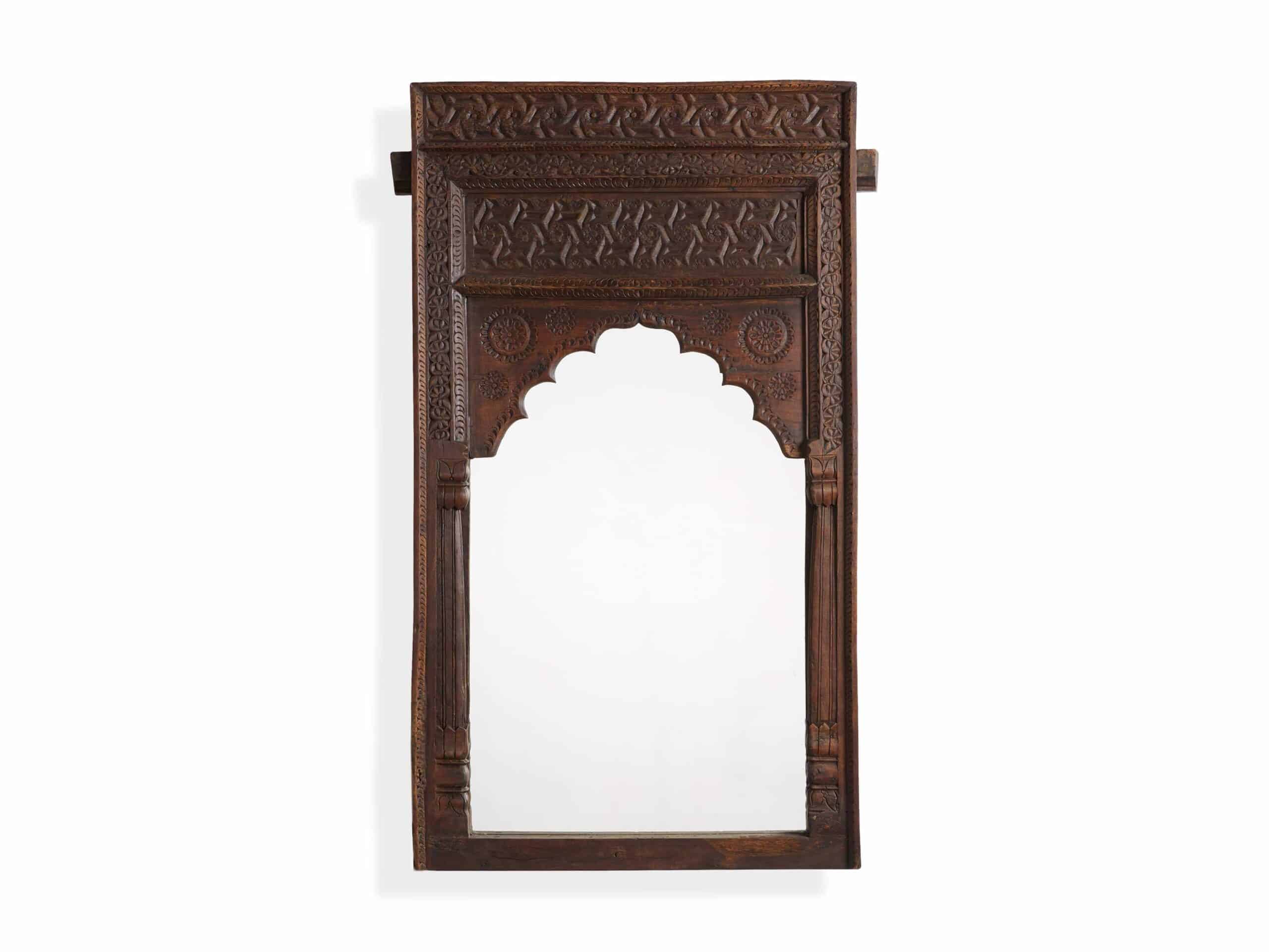 A wall-mounted wooden mirror with a carved wooden frame and a rectangular mirrored surface.
