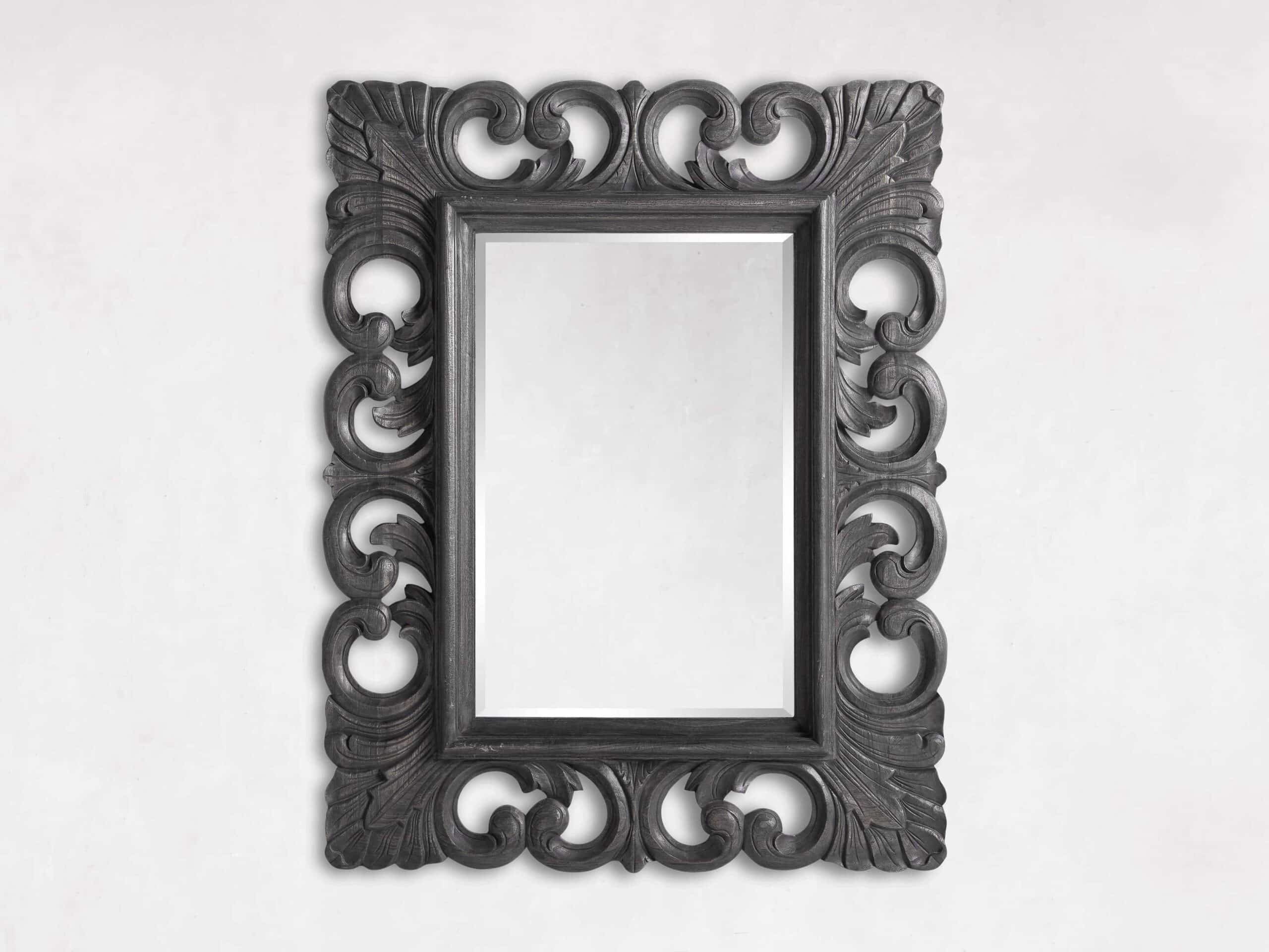 A rectangular, wooden wall-mounted mirror with intricate handcarved details.